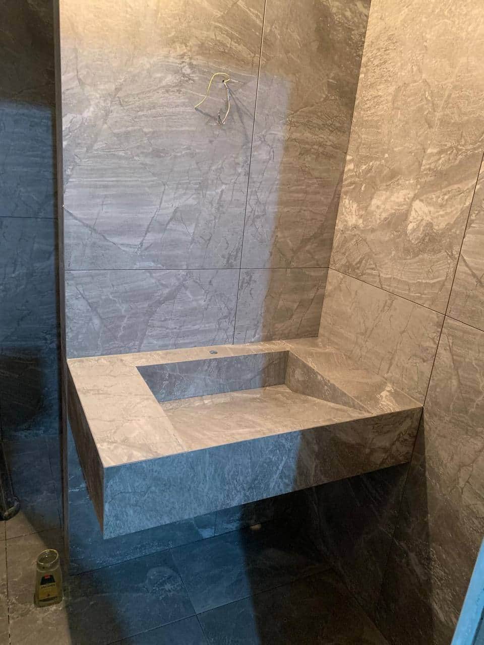 Detaliu de execuție ceramică: muchie exterioară tăiată la 45°, fără profil metalic, și racord curat la peretele placat.
